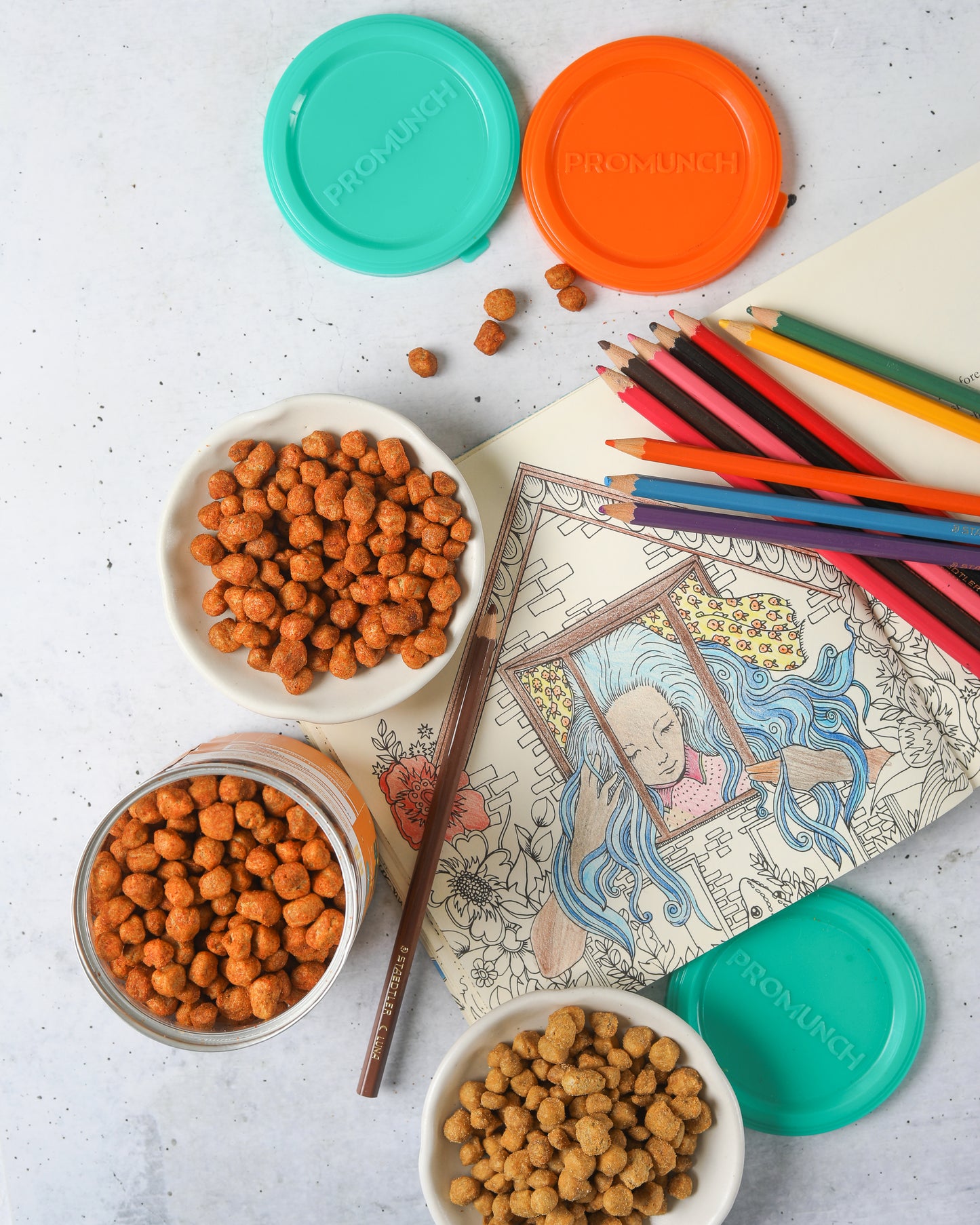roasted soya snacks, packed with 48% protein, alongside a creative coloring setup with vibrant pencils, an artbook, and colorful snack jar lids, reflecting a healthy and artistic snacking experience