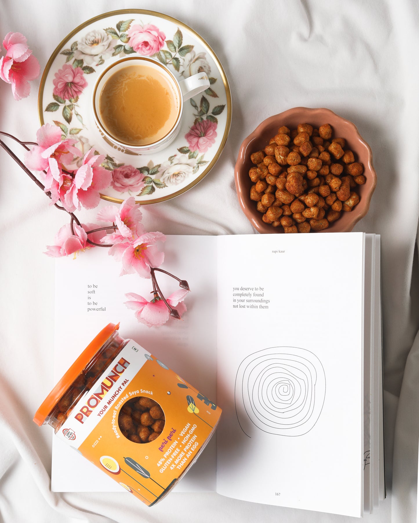 Peri Peri Roasted Soya Snack, a floral teacup of chai, and an open book, perfect for relaxing tea-time moments. High-protein, gluten-free, and flavorful – the ideal healthy snack companion.