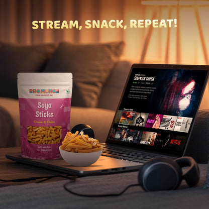 Soya Sticks in Cream & Onion flavor displayed alongside a bowl of snacks, a laptop streaming a show, and headphones, capturing a cozy binge-watching setup with the tagline 'Stream, Snack, Repeat!